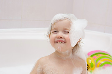 happy little child in a cap of foam in bath