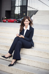 Managerin mit Mobiltelefon sitzt auf einer Treppe