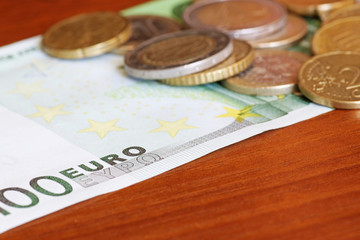 coins on one hundred euro banknote