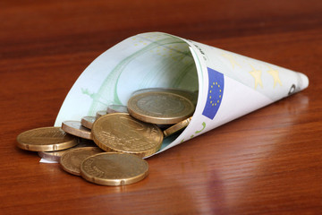 Euro coins in rolled one hundred euro banknote