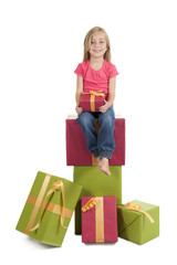 little girl seated on a stack of birthday presents