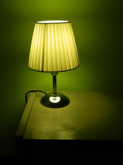 Detail color photography of small lighting lamp on wooden table. Lighting lamp in the evening. Cozy home still life with simple small lamp.