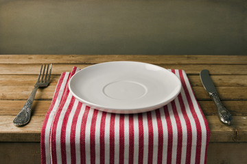 Empty plate with fork and knife on wooden table