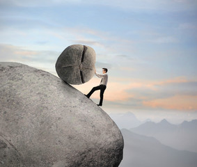 Businessman pushing a boulder on a rock © olly