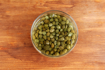 Jar with capers on wooden background