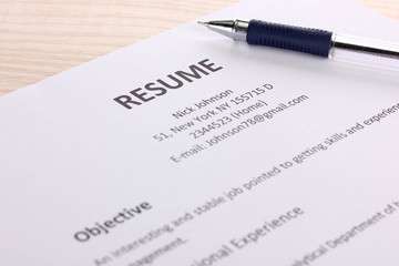 Closeup of resume with pen on wooden table