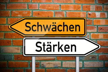 Obraz premium Wegweiser auf Ziegelsteinwand mit Schwächen und Stärken