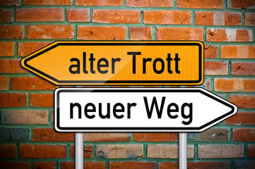 Fototapeta premium Wegweiser auf Ziegelsteinwand mit alter Trott und neuer Weg