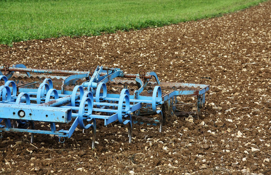 A blue plough in the field ready for spring farming