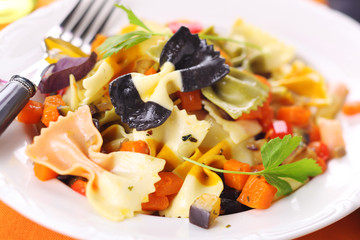 Pasta farfalle with vegetables on white plate.