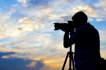 Silhouette of a photographer taking a picture in sunset - obrazy, fototapety, plakaty