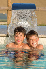 Zwei Jungen unter dem Wasserstrahl im Swimmingpool - Abkühlung