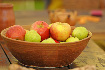 apples in a clay bowl on a wooden table