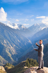 businessman with laptop at the top of the mountain