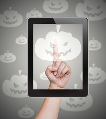 Hand pushing pumpkin button of tablet on a touch screen