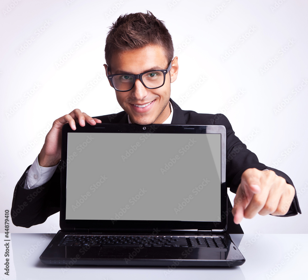 Wall mural man sitting at office desk with laptop pointing