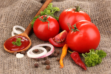 Ketchup and ripe tomatoes on sacking close-up