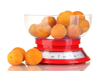 Ripe apricots in kitchen scales isolated on white