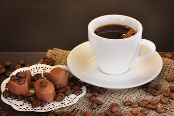 Cup of coffee on wooden table on brown background