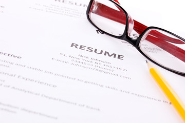 Closeup of resume with pencil and glasses on table