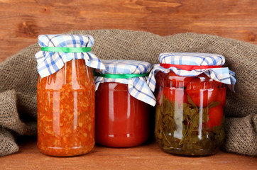 Jars with canned vegetables on wooden background close-up
