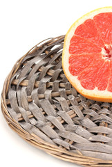 Half of ripe grapefruit on wicker mat isolated on white