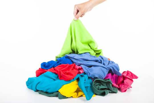 hand pick up a shirt in pile of colorful clothes
