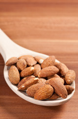 Almonds on spoon on a wooden background.  Side lightening.