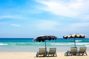 Beach chairs on the white sand beach with cloudy blue sky