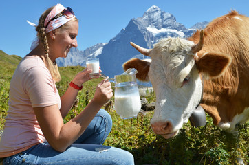 Girl with a jug of milk and a cow. Switzerland