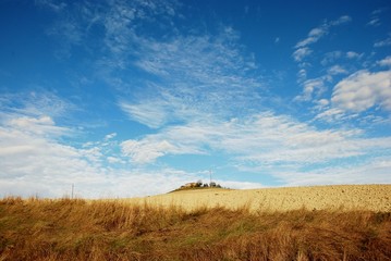 rudere nella campagna toscana con cielo azzurro e nubi