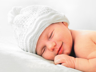 smiling newborn baby in white hat