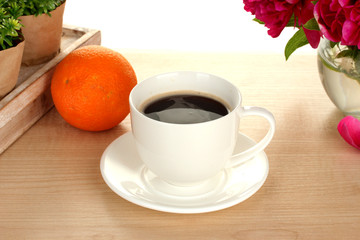 cup of coffee, orange and flowers on table in cafe