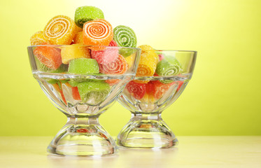 colorful jelly candies in  in glass bowls on green background.