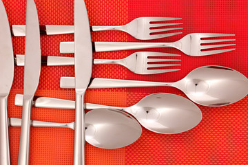 forks, knifes and spoons on red mat close-up