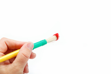 Female hand holding brush with red paint, isolated over white.