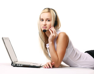 A lying woman on a sofa with a laptop and a headset indoors