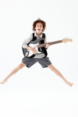 Little boy jumping and holding a guitar