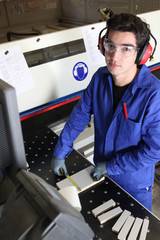 Young factory worker operating cutting machine