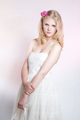 Fototapeta na wymiar Young blonde girl posing in studio in white dress