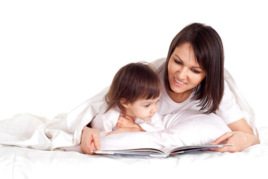 A nice Caucasian mother with her daughter lying with a book