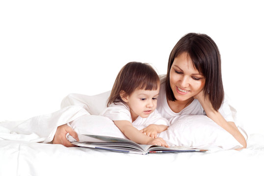A beautiful Caucasian mama with her daughter lying with a book