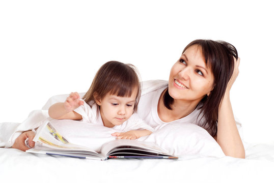 A nice Caucasian mama with her daughter lying with a book
