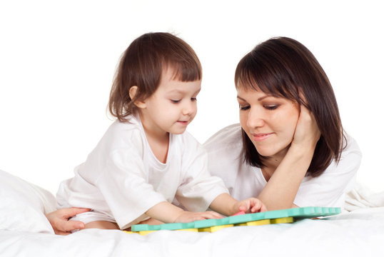 A beautiful Caucasian mama with her daughter play with a mat
