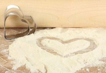 Cookie cutter with rolling pin on wooden table close-up