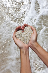 Mellow heart shaping female hands at beach
