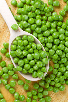 Fresh wet green peas on the wooden spoon