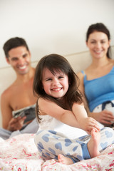 Family Relaxing In Bed Together