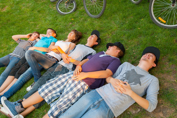 Teenage boys and girls lying on the grass after riding bicycles