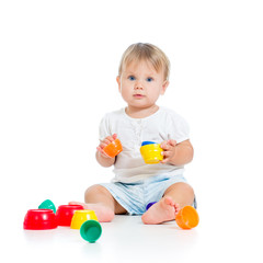 Funny little child is playing with toys while sitting on floor,